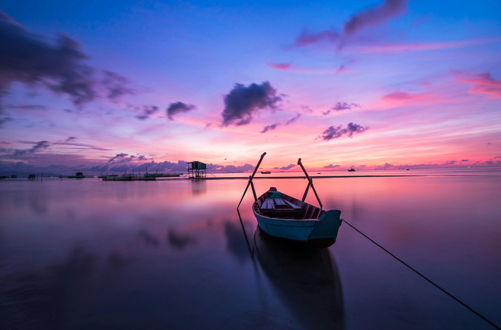 A tranquil tropical sunrise with a lone boat on calm waters.